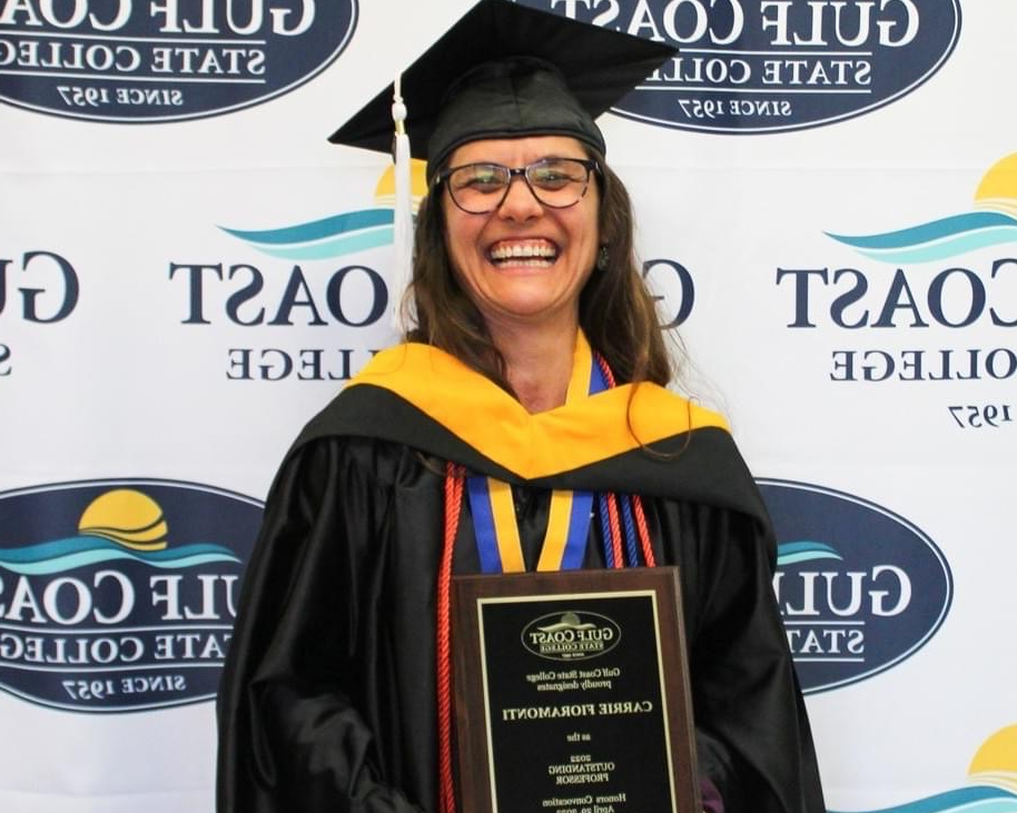 An instructor in a cap and gown with tassels